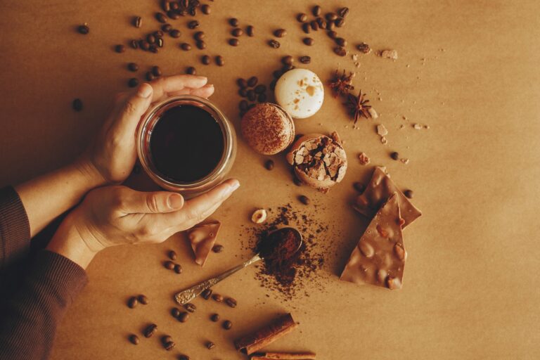 Hands holding glass cup with fresh coffee and roasted beans